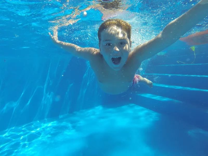 Kind taucht im Freibad, Badespaß für die ganze Familie